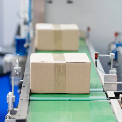 Paquetes en cinta verde bajo inspección automatizada en línea de E-commerce