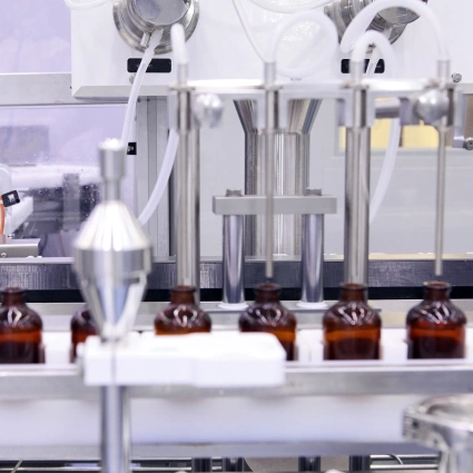 Cabezal dosificador llenando viales con solución líquida en proceso de envasado farmacéutico