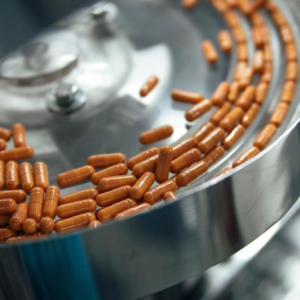 Cápsulas siendo alineadas en sistema rotativo de llenado para envase farmacéutico