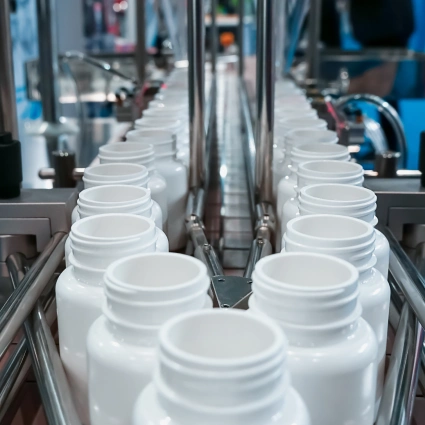 Botellas farmacéuticas de polietileno siendo llenadas y tapadas en línea automatizada