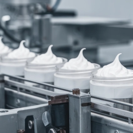 Línea de envasado llenando tarros con crema facial de forma automatizada en entorno estéril