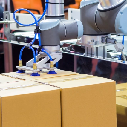 Brazo robótico colocando cajas sobre una cinta para operaciones de logística E-commerce.