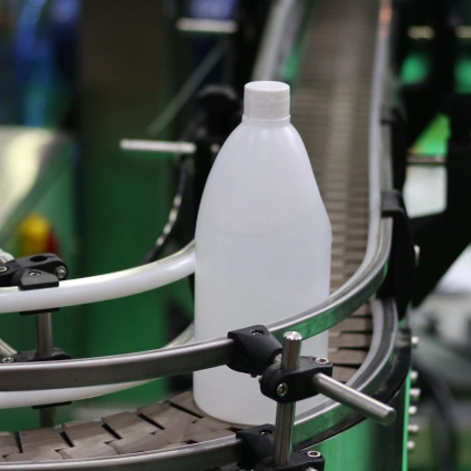 Botellas plásticas desplazándose por cinta de producción
