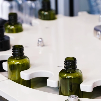 Frascos de vidrio para sérums o aceites esenciales moviéndose por estación rotativa automatizada